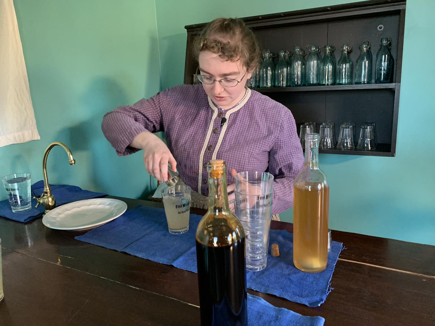 A person dressed in period time clothes pouring old fashioned soda water 