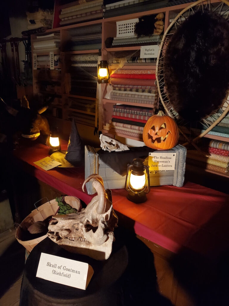 A display in the emporium of oddities, showing a skull of a goat man, a jack o' lantern and other items.