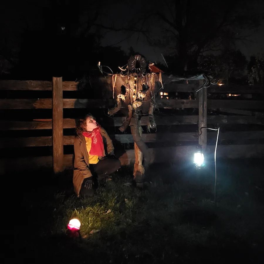 A woman stands looking up at a spooky scarecrow at a photo opportunity at Halloween Legends & Lore.